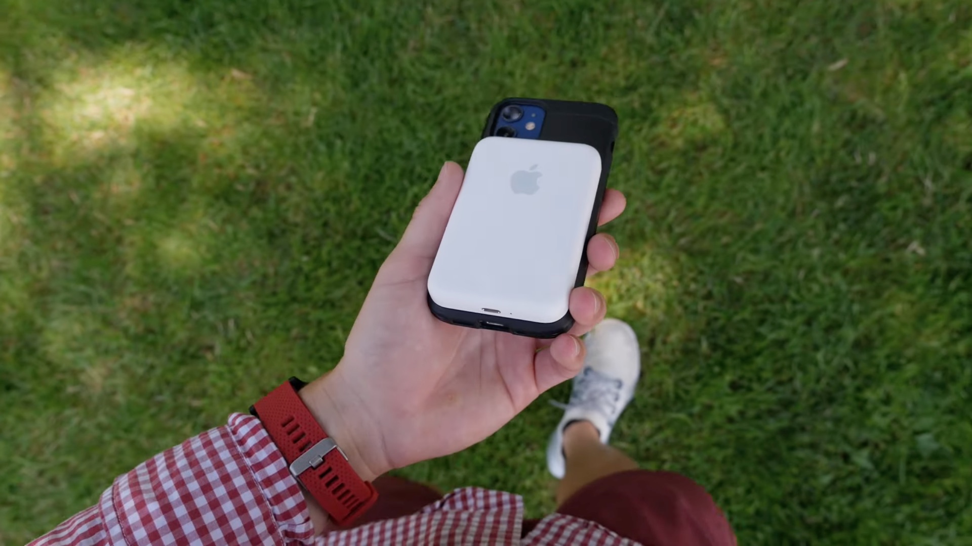 La batterie MagSafe d'Apple est vue collée à l'arrière d'un iPhone, qui repose dans la paume de la main d'un jeune, dans cette image fixe tirée de la revue vidéo de l'accessoire par la BID
