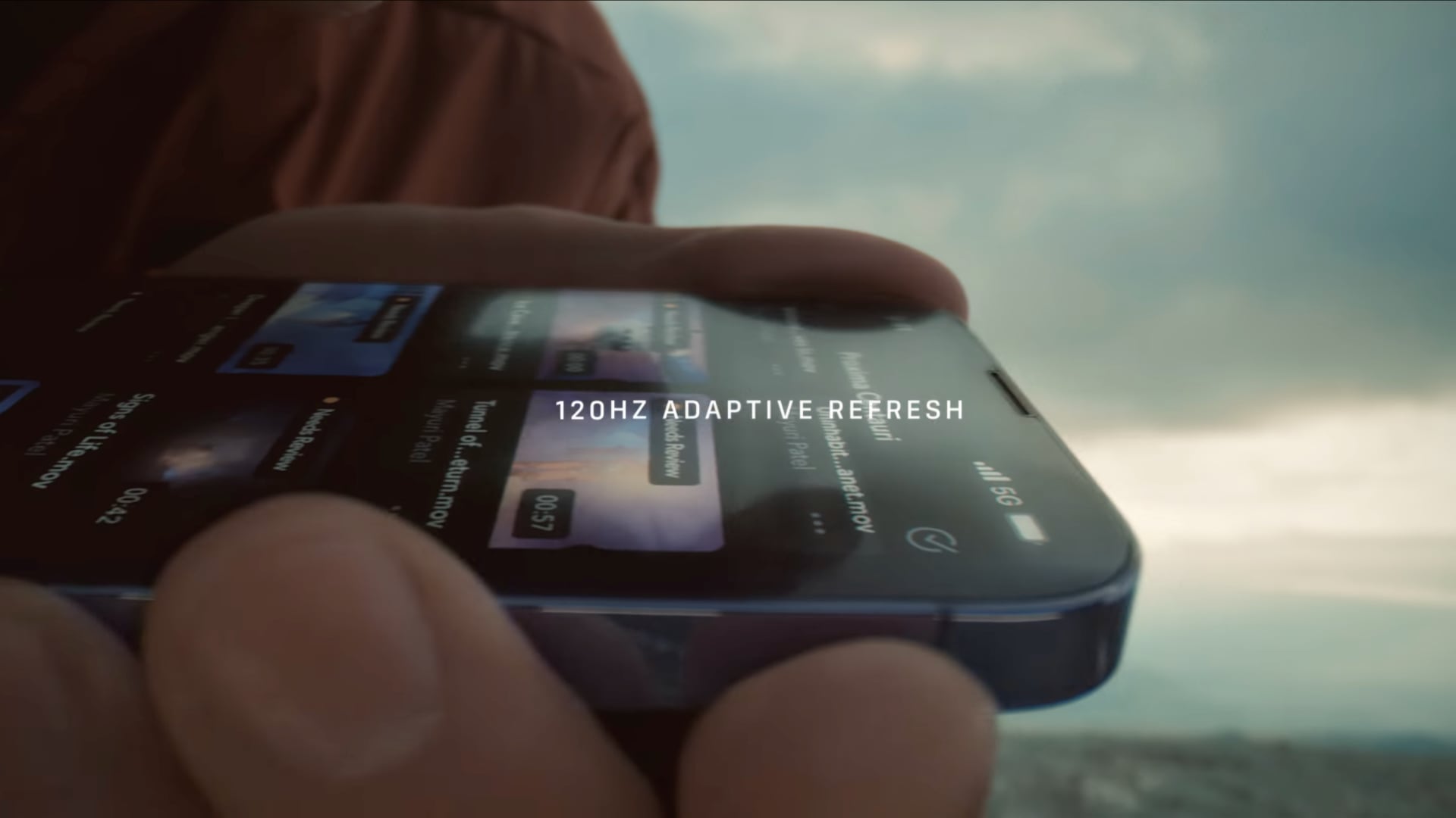 Image de la vidéo YouTube d'Apple montrant la technologie ProMotion en action, avec une main tenant un iPhone 13 Pro et faisant défiler une liste et le titre "Taux de rafraîchissement adaptatif de 120 Hz" superposé sur le dessus