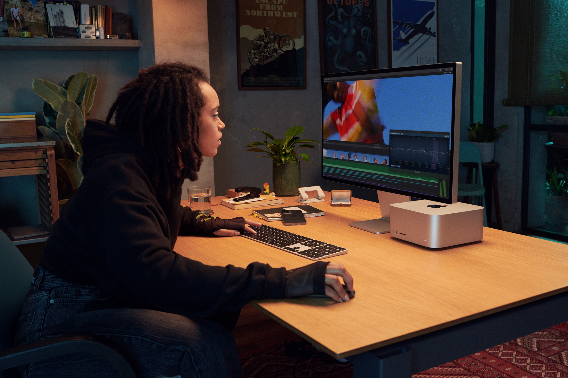 Dans cette image marketing d'Apple, un professionnel de la création est représenté assis à son bureau et utilisant un ordinateur Mac Studio connecté à un Studio Display.