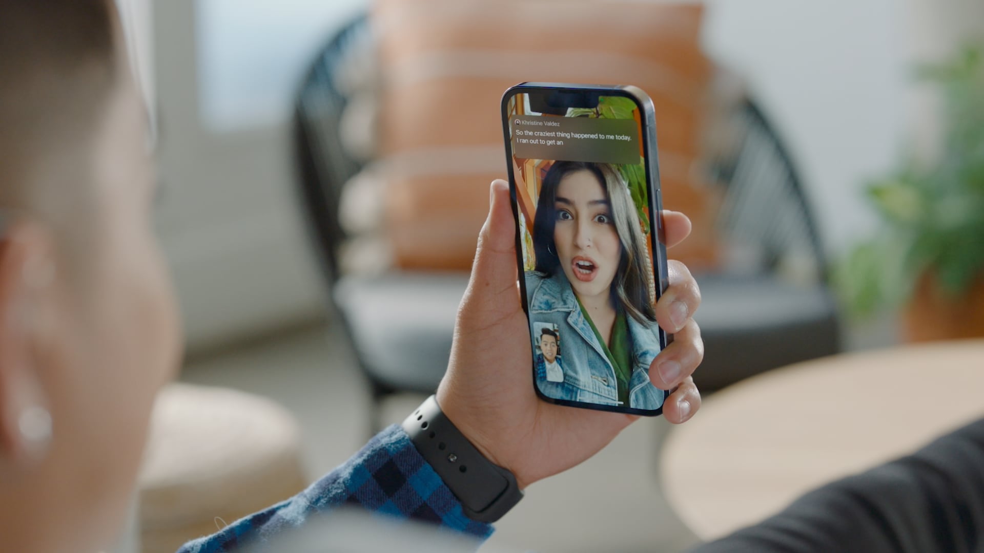 Une photographie montrant un iPhone tenu dans la main d'une personne, montrant la fonction Live Captions en action lors d'un appel vidéo FaceTime