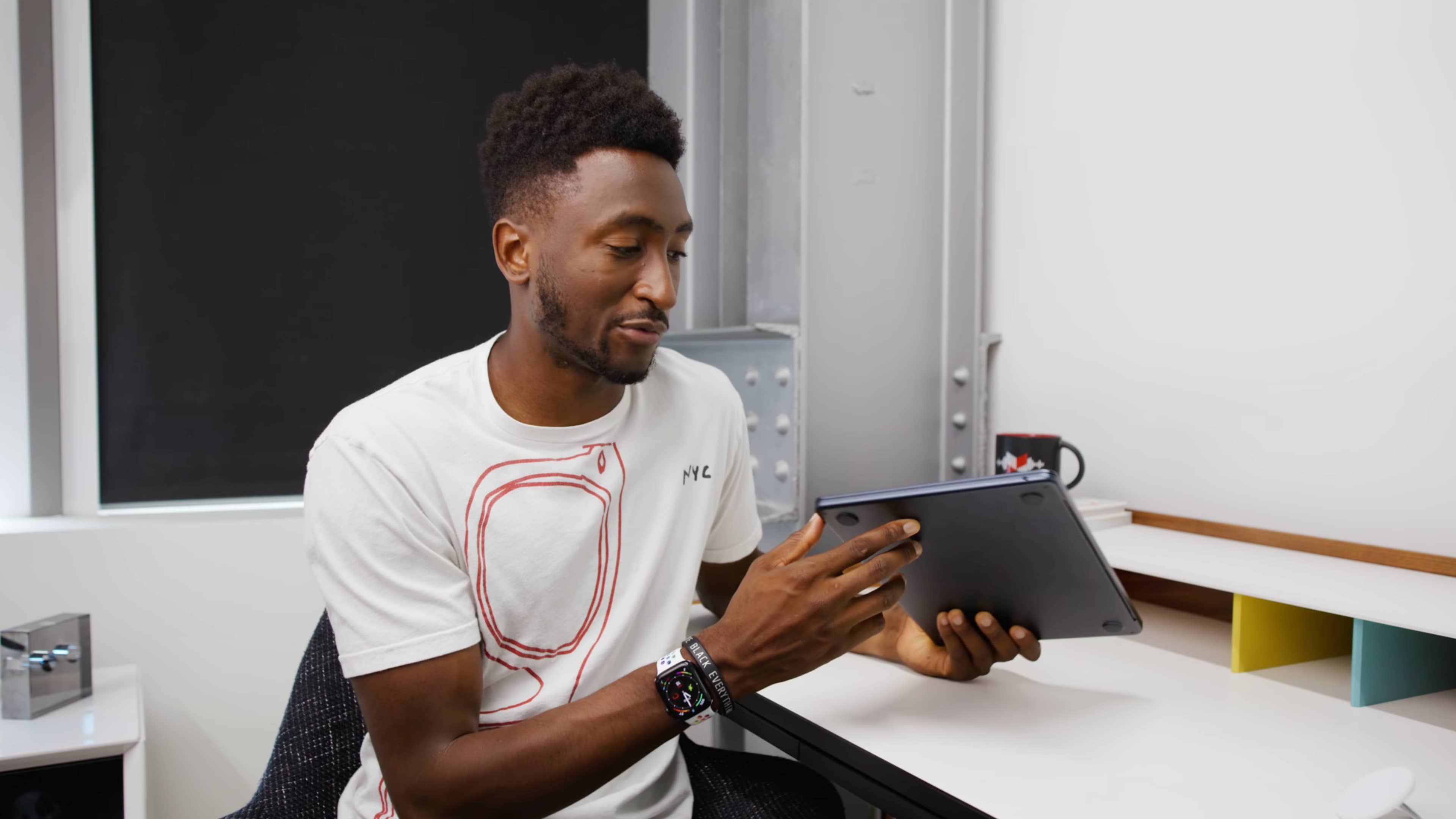 YouTuber Marques Brownlee est dans son studio, tenant l'ordinateur portable MacBook Air d'Apple dans la couleur minuit et inspectant les entailles autour des ports USB-C