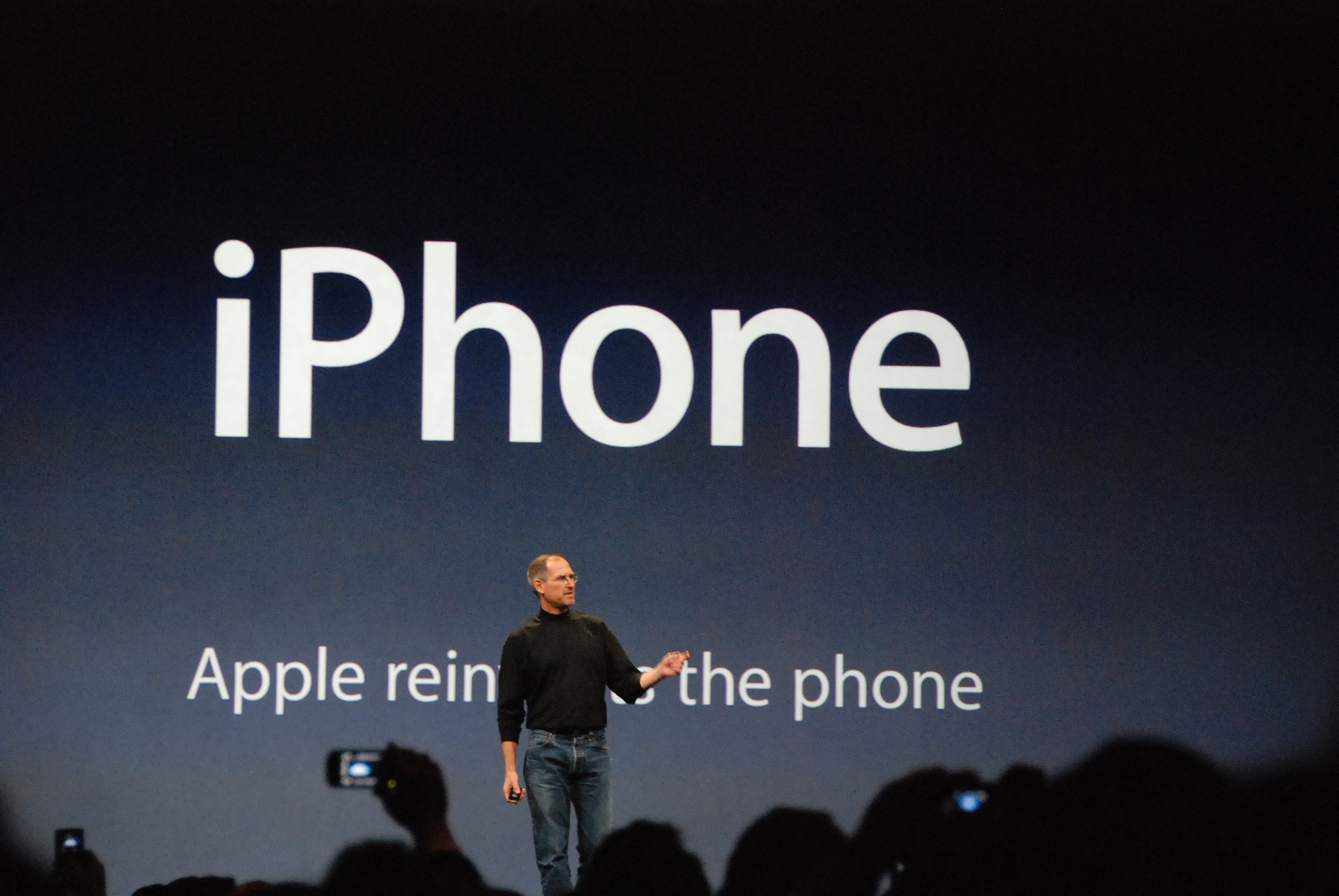 Steve Jobs debout devant la diapositive lors de l'introduction de l'iPhone en janvier 2007 montrant le slogan "Apple réinvente le téléphone"