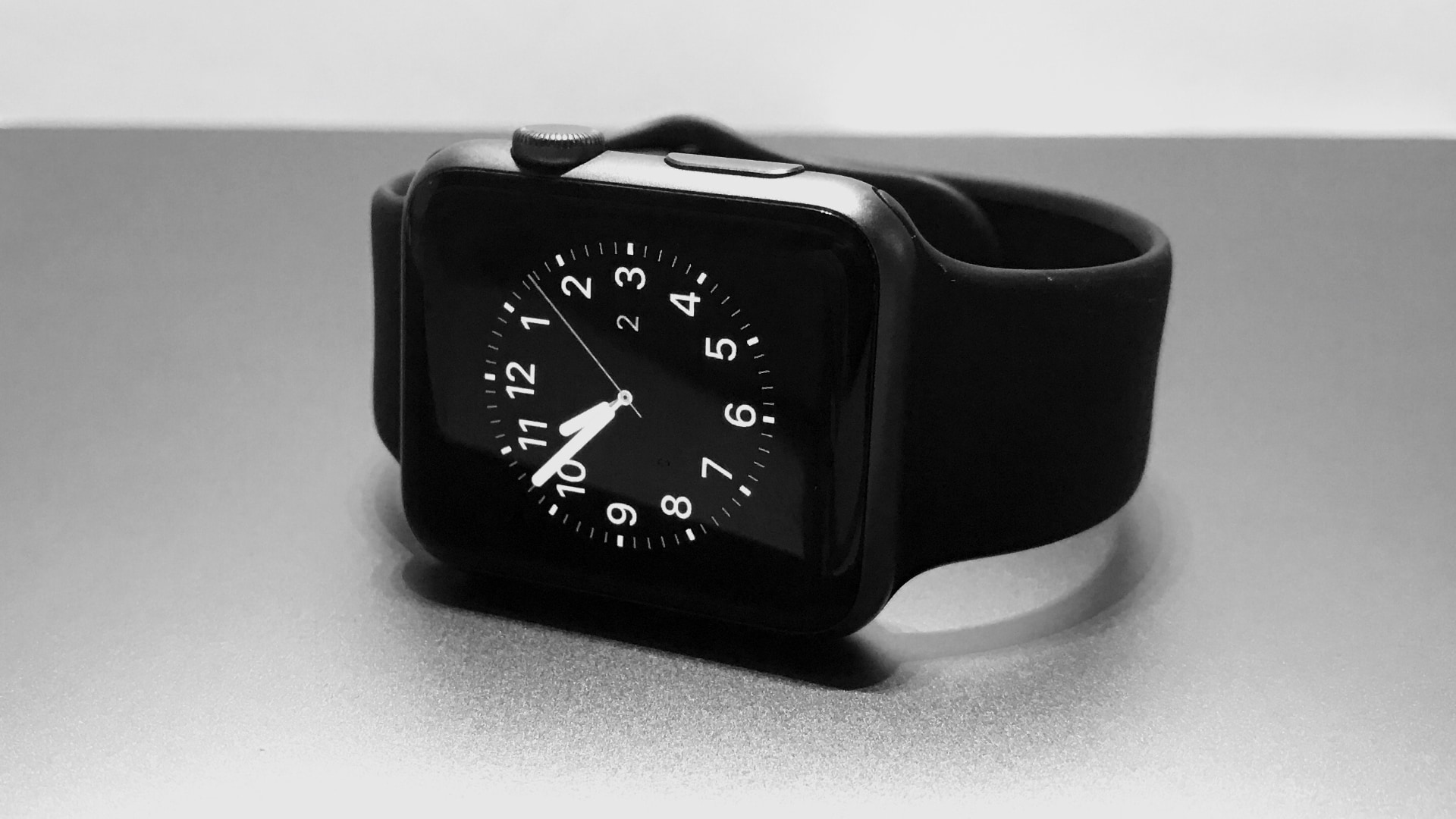 Apple Watch noire avec bracelet sport noir, assise sur le côté