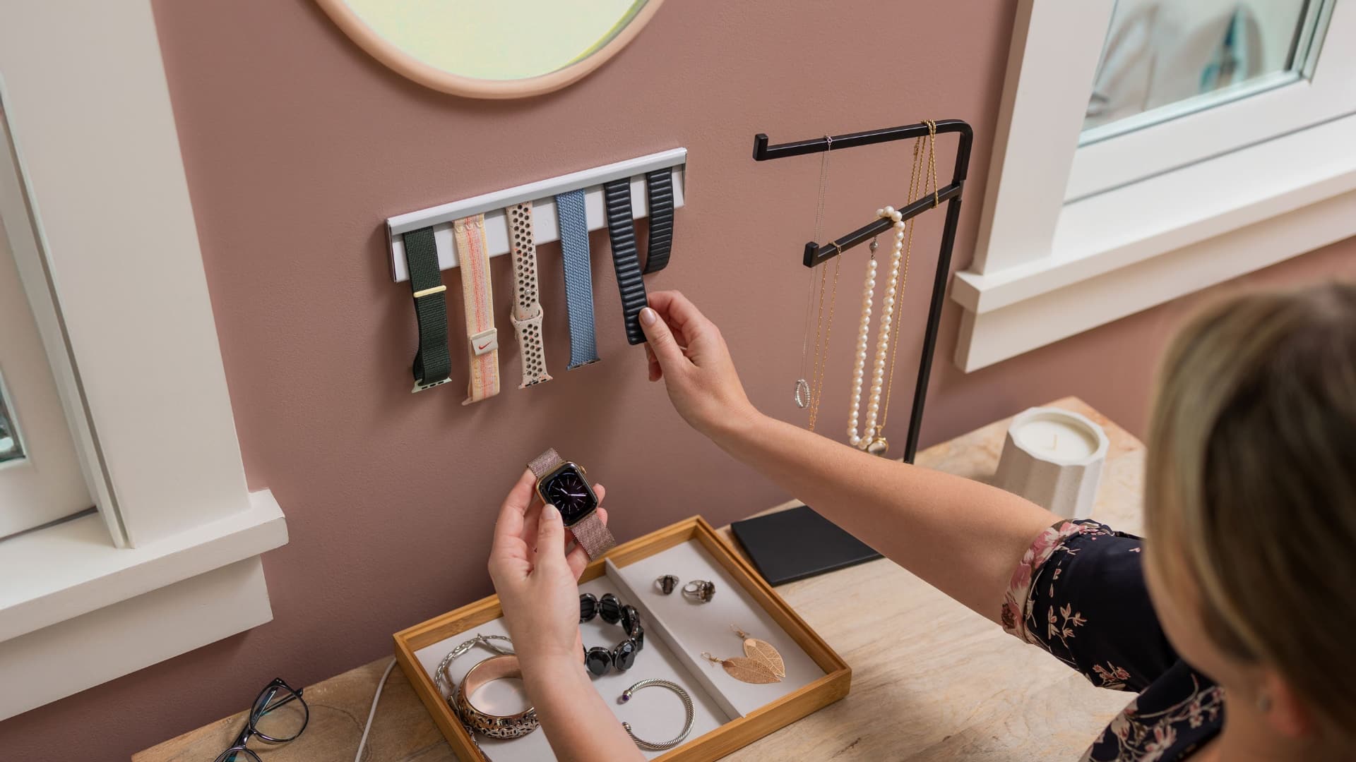 Female hand retrieving an Apple Watch band from Twelve Sotuh's wall mount